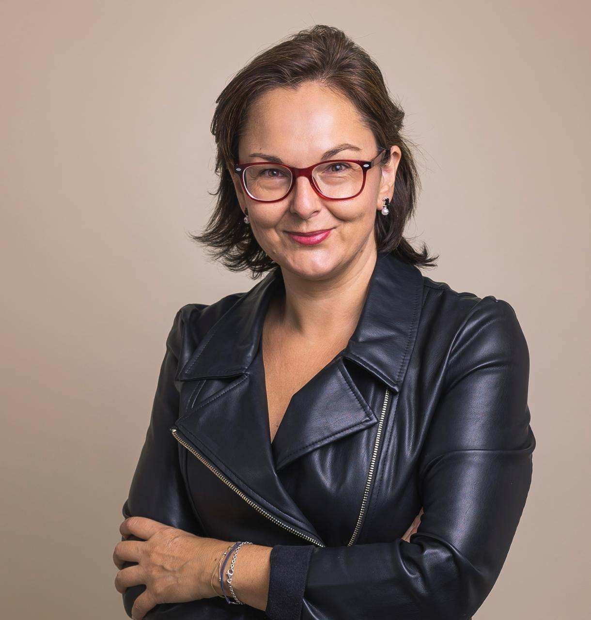 Retrato profesional de Mónica Sordo con brazos cruzados en fondo claro