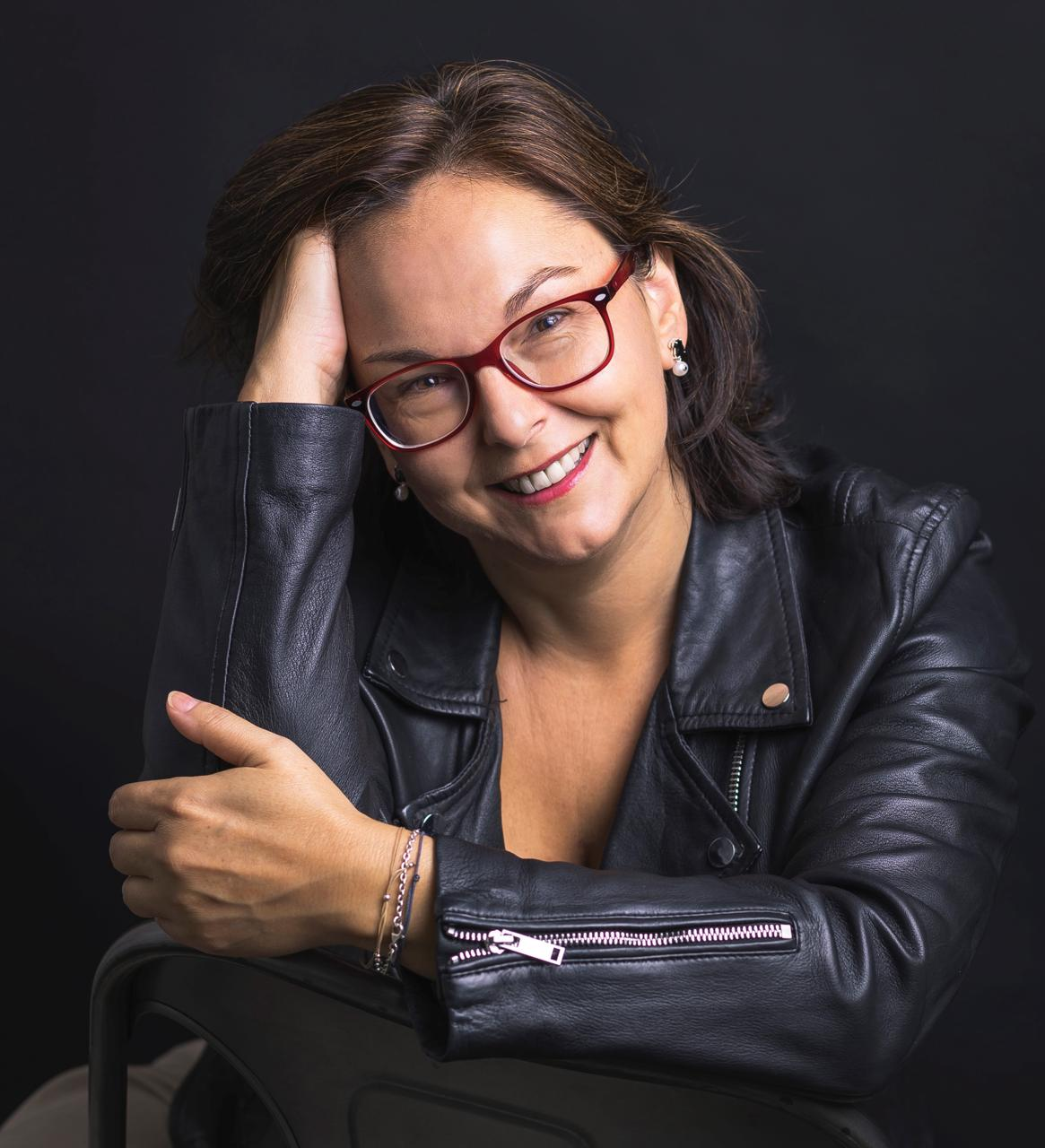 Retrato profesional de Mónica Sordo sentada en fondo negro